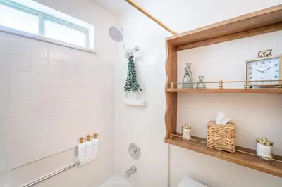 a bathroom with a shower and a clock on the wall at The Deco Retreat - UNR - Pet Friendly in Reno