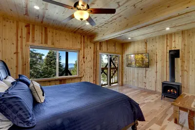 a bedroom with a bed and a fireplace and a ceiling fan at Tall Pine Chalet home in Stateline