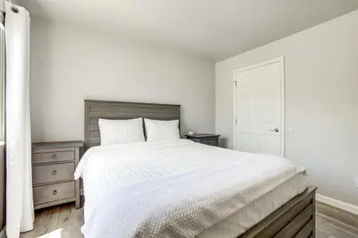a white bedroom with a large bed and a dresser at 3 Mi to Dtwn Gated Condo with Patio in Reno! in Reno