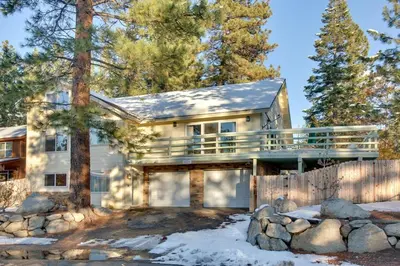 a house with a wrap around porch in the woods at Sequoia Chalet home in Stateline