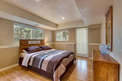 a bedroom with a bed and a table and two windows at Sequoia Chalet home in Stateline