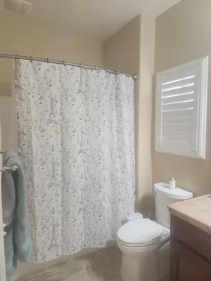 a bathroom with a toilet and a shower curtain at Tanglewood Place in Visalia