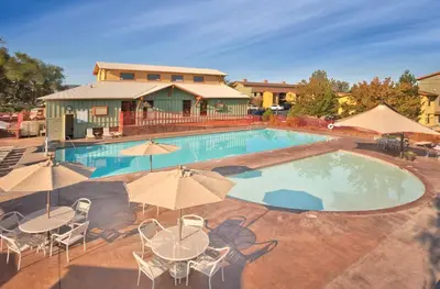 a large swimming pool with tables and chairs and umbrellas at Wyndham Angels Camp 2BR Apartment with Resort Access in Angels Camp