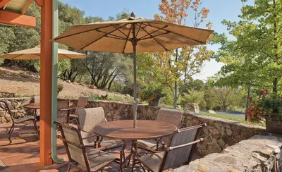 a table and chairs with an umbrella on a patio at Wyndham Angels Camp 2BR Apartment with Resort Access in Angels Camp