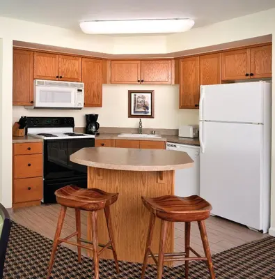 a kitchen with a white refrigerator and wooden cabinets at Wyndham Angels Camp 3BR Apartment with Resort Access in Angels Camp
