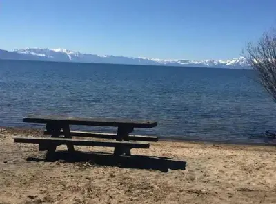 a picnic table sitting on the shore of a lake at #10 Lakeside Great Location Beach Access Dogs ok in Kings Beach