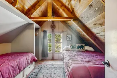 a attic bedroom with two beds and a window at Little Cozy Cabin in Shaver Lake