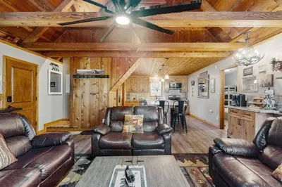 a living room with leather furniture and a ceiling fan at Little Cozy Cabin in Shaver Lake