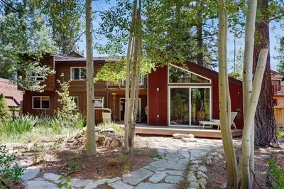 a house in the woods with a patio and trees at Serenity Summit in South Lake Tahoe
