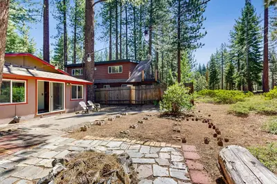 a house with a garden in front of a forest at The Rikz Cabin in South Lake Tahoe
