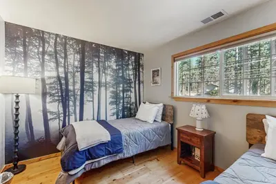a bedroom with a bed and a window with trees at The Rikz Cabin in South Lake Tahoe