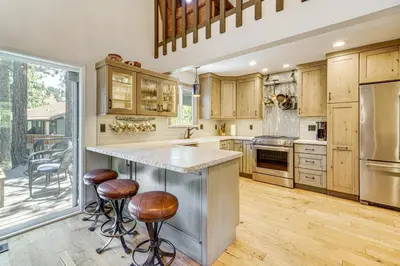 a kitchen with wooden cabinets and a large island with bar stools at Walk to Diamond Peak Luxe Chalet with Mtn-View Deck in Incline Village