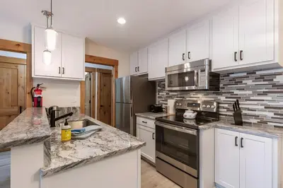 a kitchen with white cabinets and granite counter tops at 1BDR Condo in the Heart of Olympic Valley! in Tahoe City