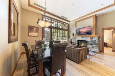 a living room with a table and a fireplace at Catamount Lodge 101 by East West Hospitality in Truckee