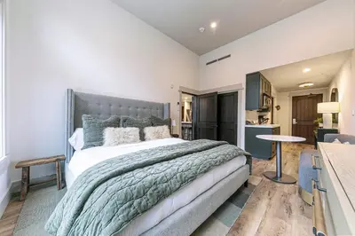 a bedroom with a large bed and a kitchen at Catamount Lodge 101A by East West Hospitality in Truckee