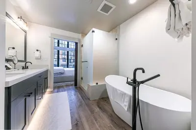 a white bathroom with a tub and a sink at Catamount Lodge 101B by East West Hospitality in Truckee