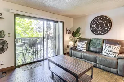 a living room with a couch and a clock on the wall at Walk to Virginia Lake Reno Condo with Balcony! in Reno