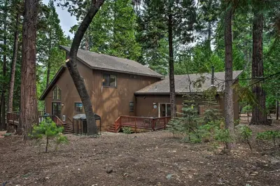a large wooden house in the middle of a forest at Game Room and Deck Pet-Friendly Camp Connell Cabin in Camp Connell