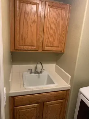a bathroom with a sink and wooden cabinets at Furnished five bedroom and gated community in Patterson