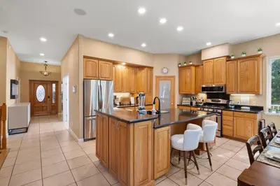 a large kitchen with wooden cabinets and white appliances at Yosemite-bound, Fun at the lake, Spacious & stylish 6 Bdr home with game room in Groveland