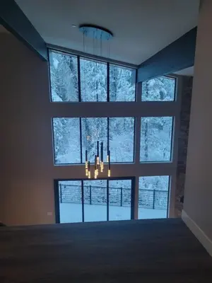a room with a large window with a chandelier at Mariposa Grove Creekside Retreat - To be featured on STAYCATION on the Destination Channel in 2026! in Fish Camp