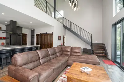 a living room with a brown leather couch and a table at Mariposa Grove Creekside Retreat - To be featured on STAYCATION on the Destination Channel in 2026! in Fish Camp