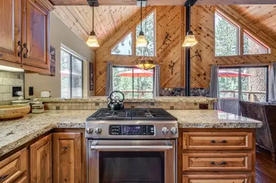 a kitchen with wooden cabinets and a stove at 1 Mi to Tahoe Donner Skiing Luxe Truckee Cabin! in Truckee