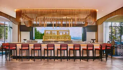 a large dining room with a bar with red chairs at Limelight Mammoth in Mammoth Lakes