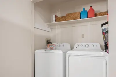 a laundry room with two white washes and shelves at Midtown Bungalow in Reno