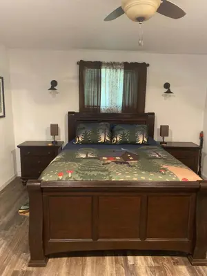 a bedroom with a large bed with a ceiling fan at Shady Creekside Cabin in Miramonte
