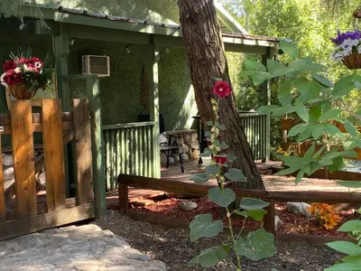 a wooden porch with a bench next to a tree at Shady Creekside Cabin in Miramonte
