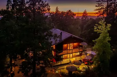 a house at night with the sun setting behind it at Vintage Sunset Villa by Bass Lake 17 miles from Yosemite National Park in Oakhurst