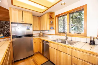 a kitchen with wooden cabinets and a stainless steel refrigerator at Alpine Retreat By Hauserman Rentals in Tahoe City