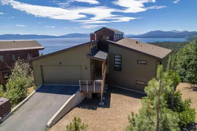 a house with a garage with a lake in the background at Beautiful View By Hauserman Rentals in Tahoe City