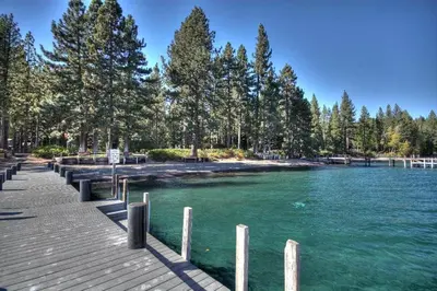 a river with a dock and trees on the shore at Beautiful View By Hauserman Rentals in Tahoe City