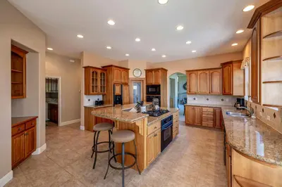 a large kitchen with wooden cabinets and a island with bar stools at Hemlock Hacienda in Groveland