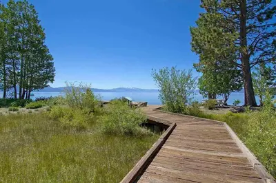 a wooden boardwalk in a field with a view of the water at Carnelian Woods # 11 By Hauserman Rentals in Carnelian Bay