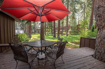 a table and chairs with a red umbrella on a deck at NorthShore # 47 By Hauserman Rentals in Tahoe City