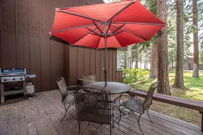 a table and chairs with a red umbrella on a deck at NorthShore # 47 By Hauserman Rentals in Tahoe City
