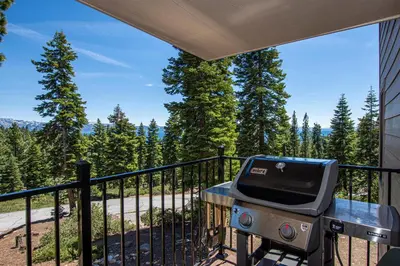a grill on a balcony with a view of trees at Carnelian Woods #128 By Hauserman Rentals in Carnelian Bay
