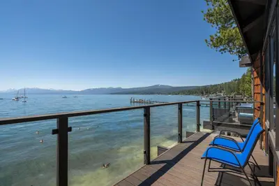 a deck with two blue chairs and the water at Star Harbor # 10 By Hauserman Rentals in Tahoe City