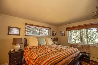 a bedroom with a bed and two windows at Coates By Hauserman Rentals in Tahoe City
