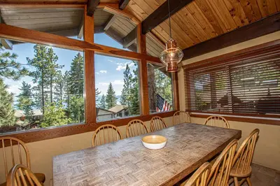 a dining room with a table and chairs and windows at Coates By Hauserman Rentals in Tahoe City