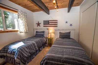 two beds in a room with an american flag on the wall at Alpine Welcome By Hauserman Rentals in Tahoe City