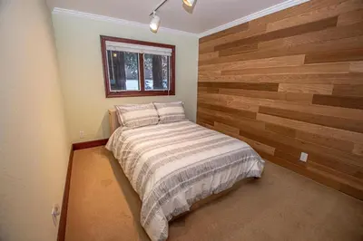 a bedroom with a bed with a wooden wall at Highlands Lodge By Hauserman Rentals in Tahoe City