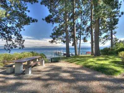 a picnic bench sitting on the grass near the water at Black Bear Haus By Hauserman Rentals in Tahoe City