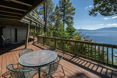 a table and chairs on a deck with a view of the water at McCown Lakefront By Hauserman Rentals in Tahoma
