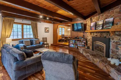 a living room with couches and a stone fireplace at Molly's Treehouse By Hauserman Rentals in Carnelian Bay