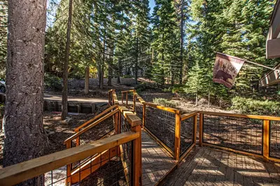 a wooden walkway leading into a forest with a tree at Casa Pasquale By Hauserman Rentals in Carnelian Bay