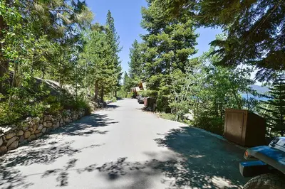 a tree lined road with a bench and trees at Rygh Lakefront By Hauserman Rentals in Carnelian Bay